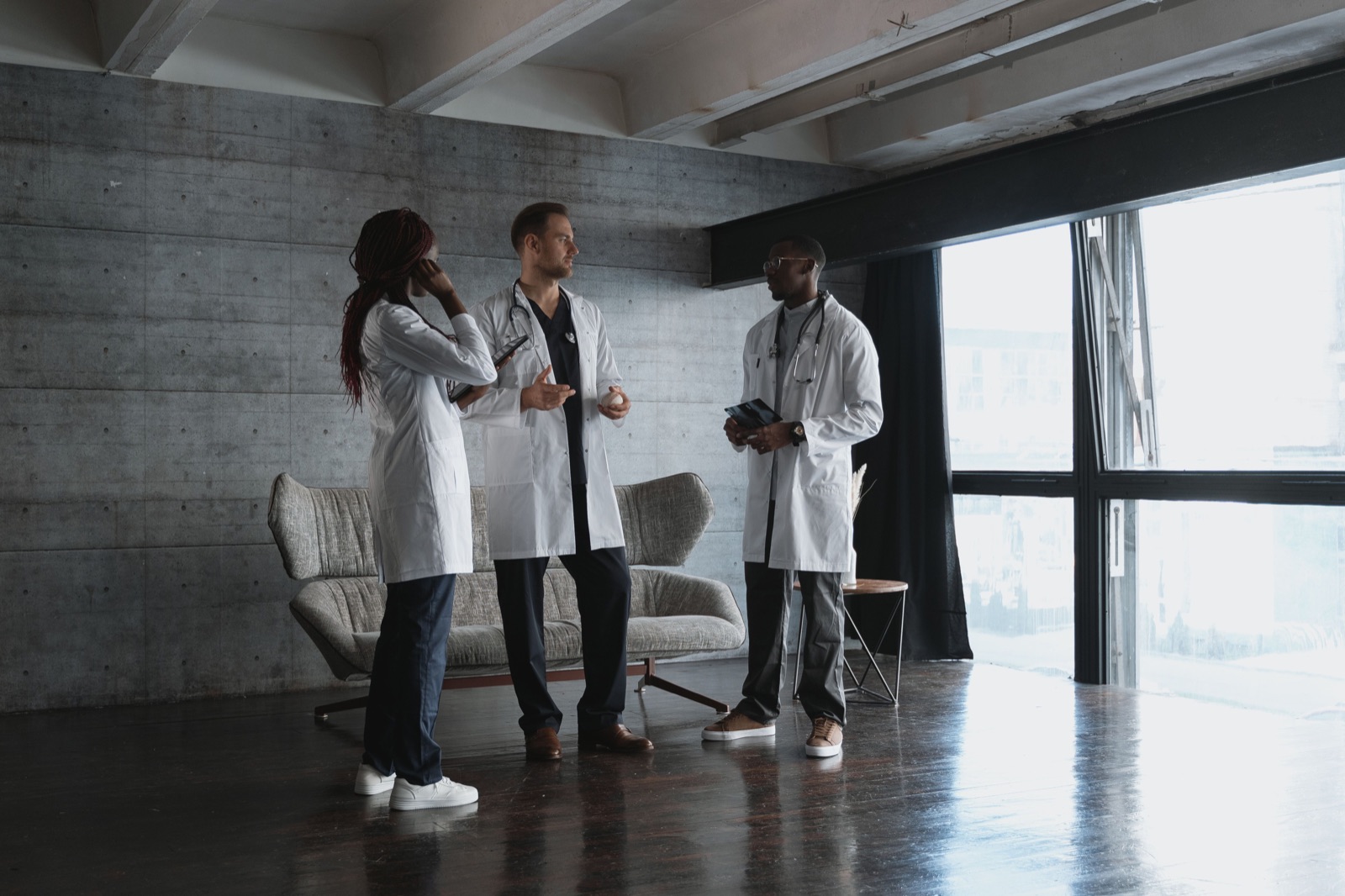 Illustrative stock photograph of three healthcare colleagues discussing work together in an office